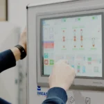 Operatore che con il dito seleziona una funzionalità dal pannello touchscreen della macchina