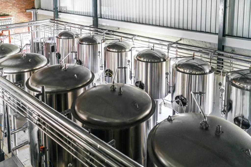 Impianto industriale con grandi serbatoi in acciaio inox e tubature.