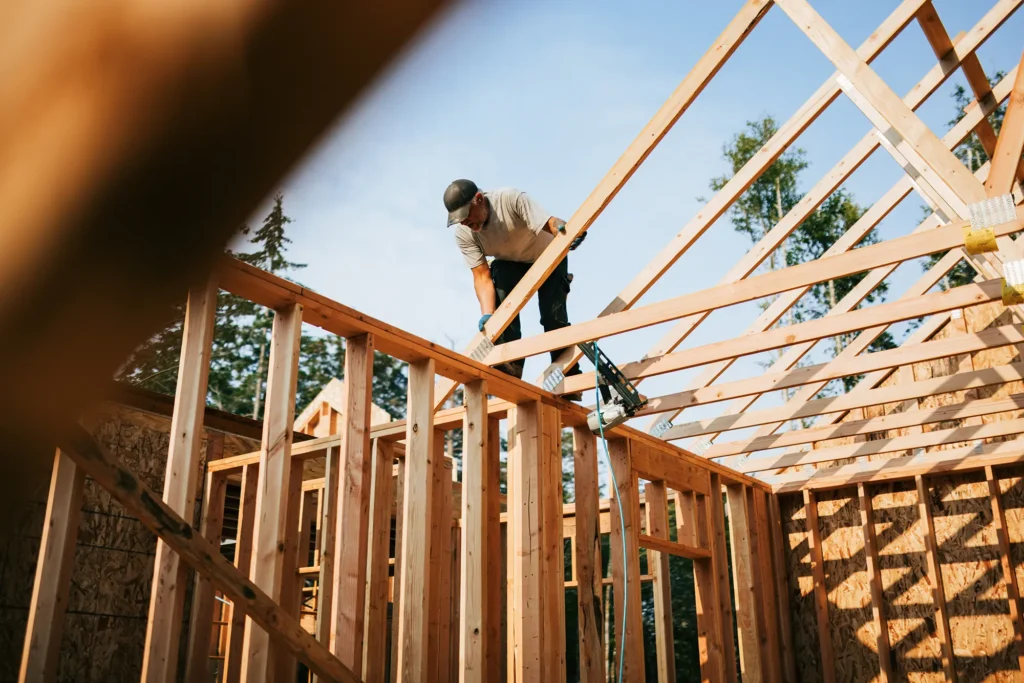 Lavoratori costruiscono una struttura in legno, probabilmente un’abitazione.