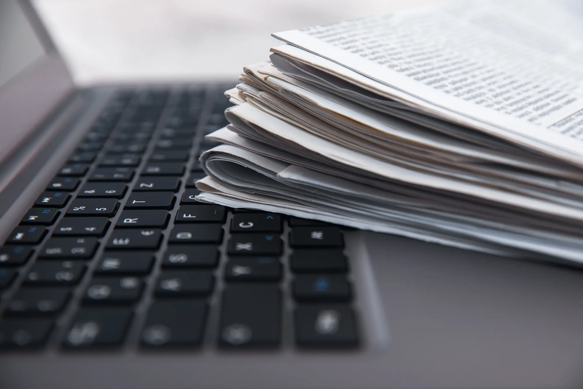 Fascicolo di documenti appoggiato su tastiera di un laptop.