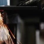 Processo di saldatura con scintille e braccio meccanico in azione.