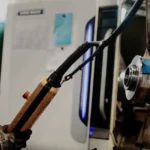 Processo di saldatura con scintille e braccio meccanico in azione.