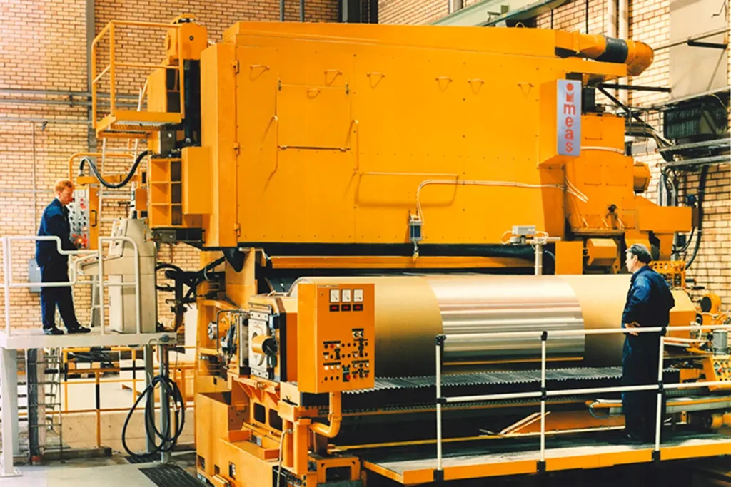 Grande macchinario giallo con due operai che ci lavorano
