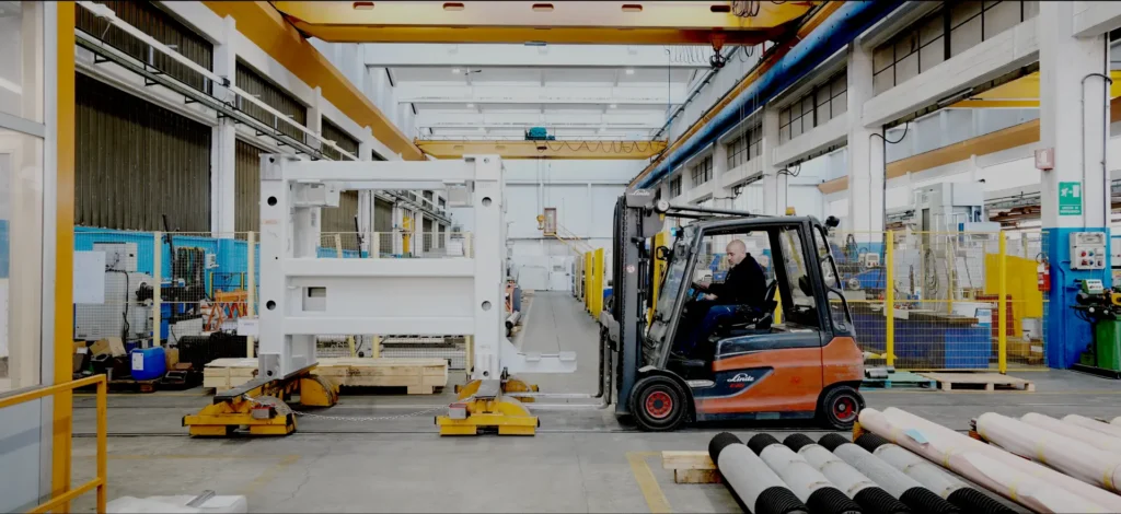 Interno di stabilimento industriale con carrelli elevatori e macchinari.